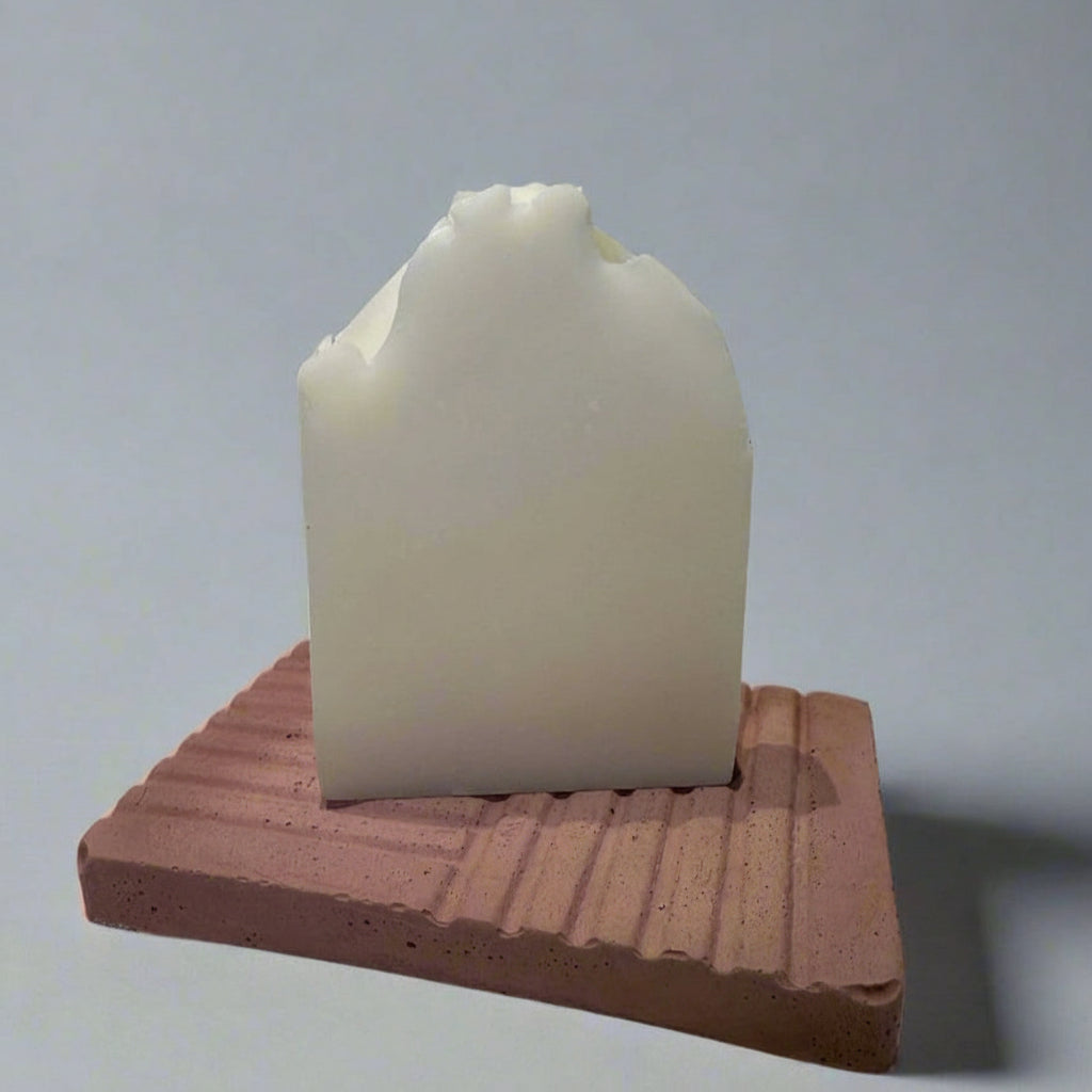 White bar of soap on a red brick stand against a gray background